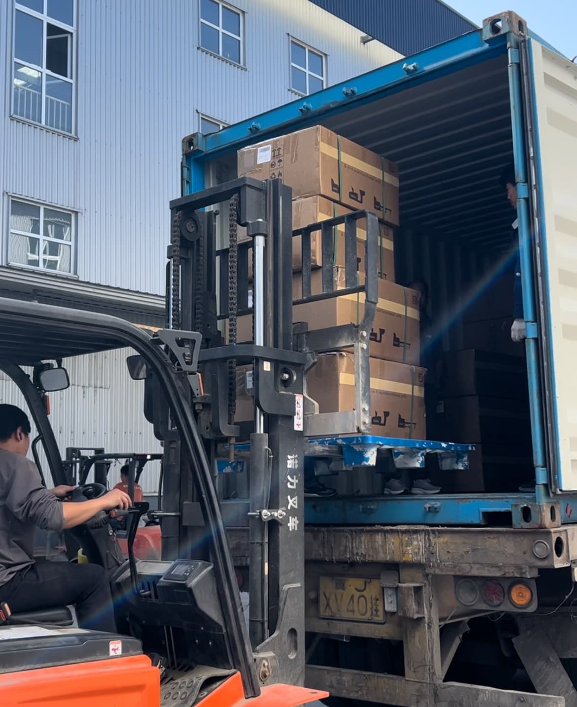 Forklift-assisted loading at the container entrance.